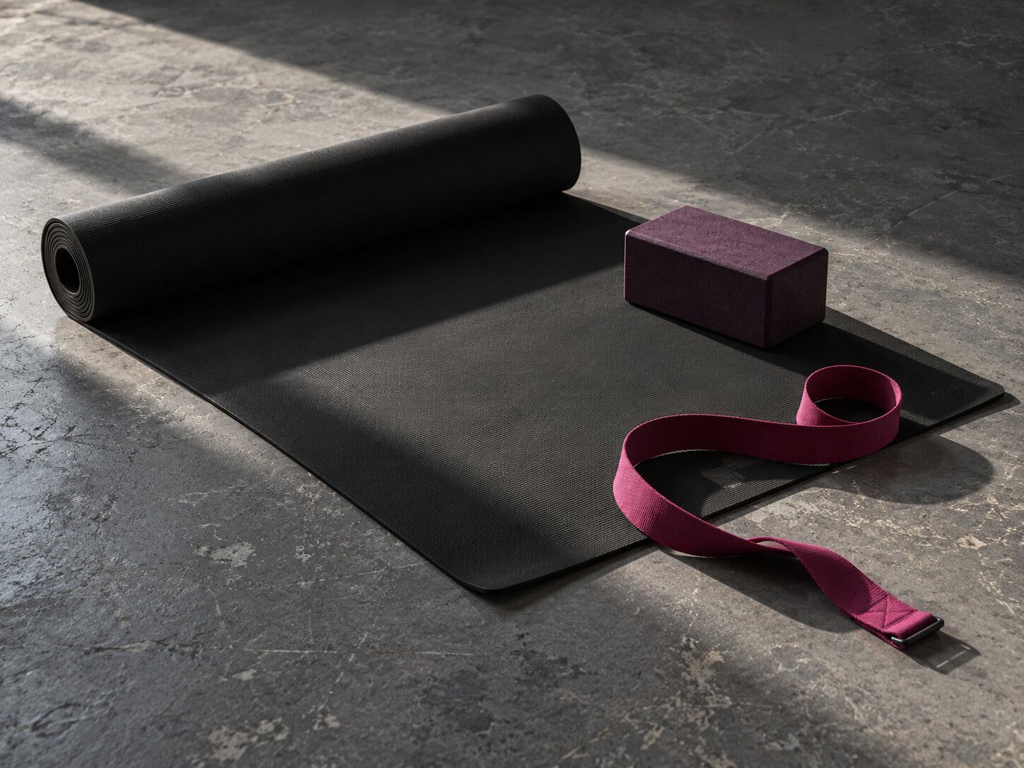 Yoga mat, aubergine block and fuchsia strap in directional studio light